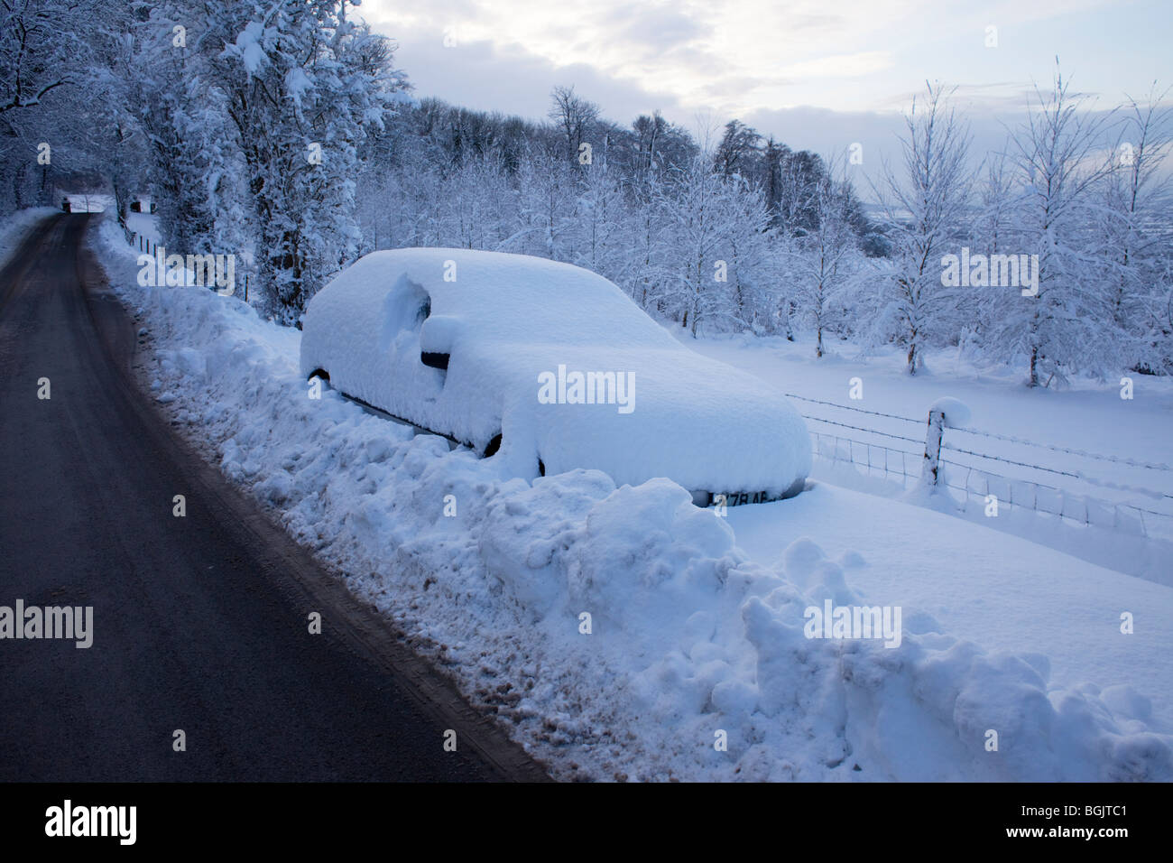 A car stranded in snow by the side of a road in Broadway, Worcestershire, UK Stock Photo