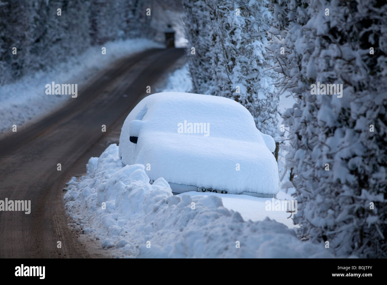 A car stranded in snow by the side of a road in Broadway, Worcestershire, UK Stock Photo