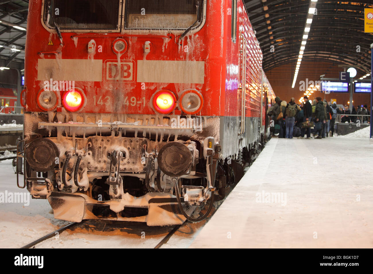 travelers boarding an icy train of German Railways (Deutsche Bahn), winter conditions on the roofed station platforms Stock Photo
