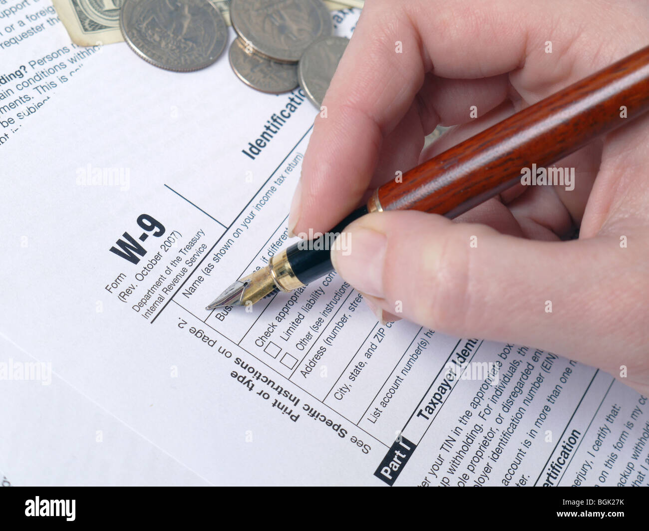 Female hand filling out W-9 income tax form with pen Stock Photo