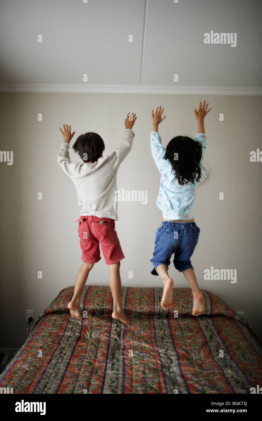 Brother and sister bounce on bed Stock Photo Alamy