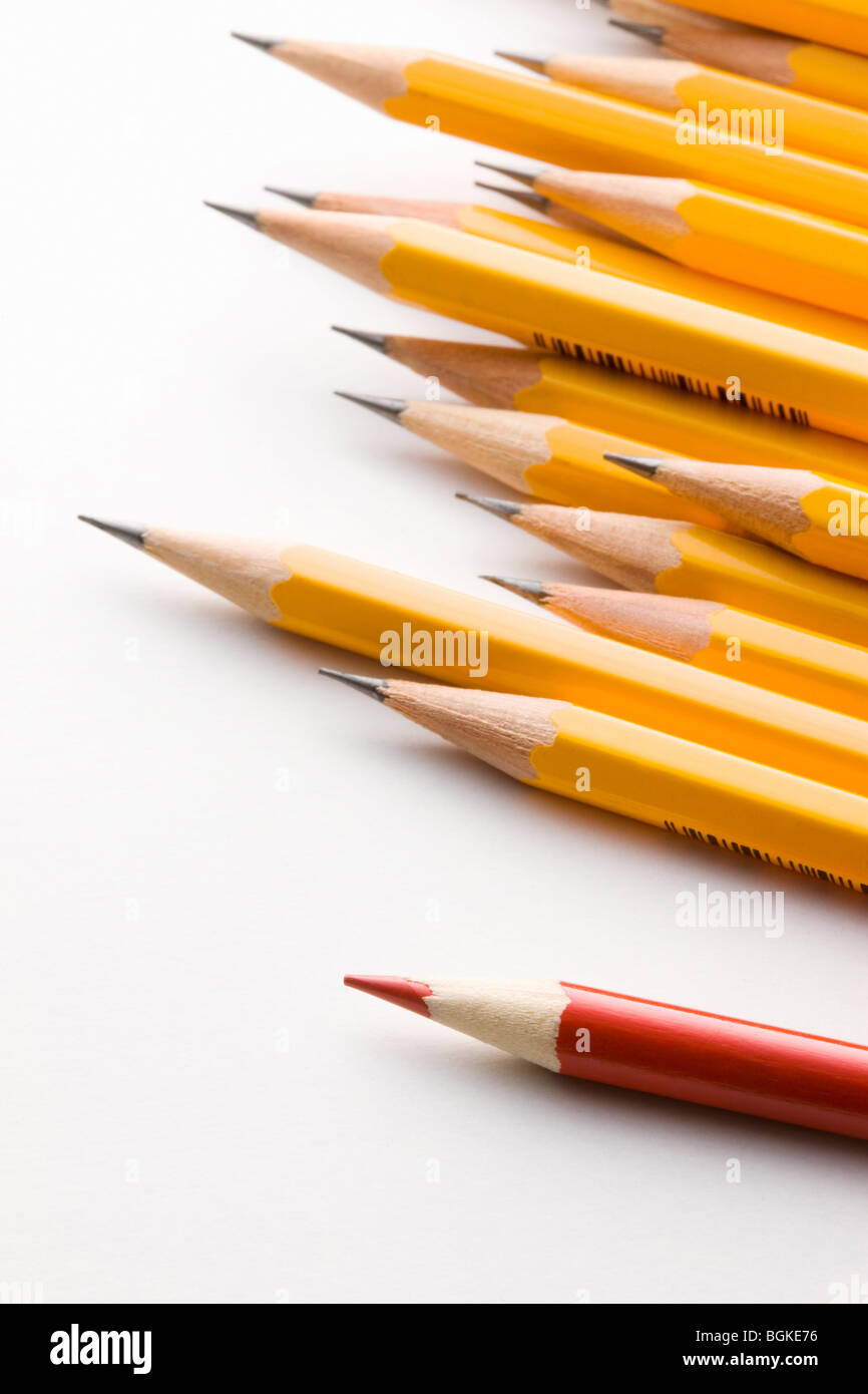 Red pencil standing out from group of yellow pencils Stock Photo