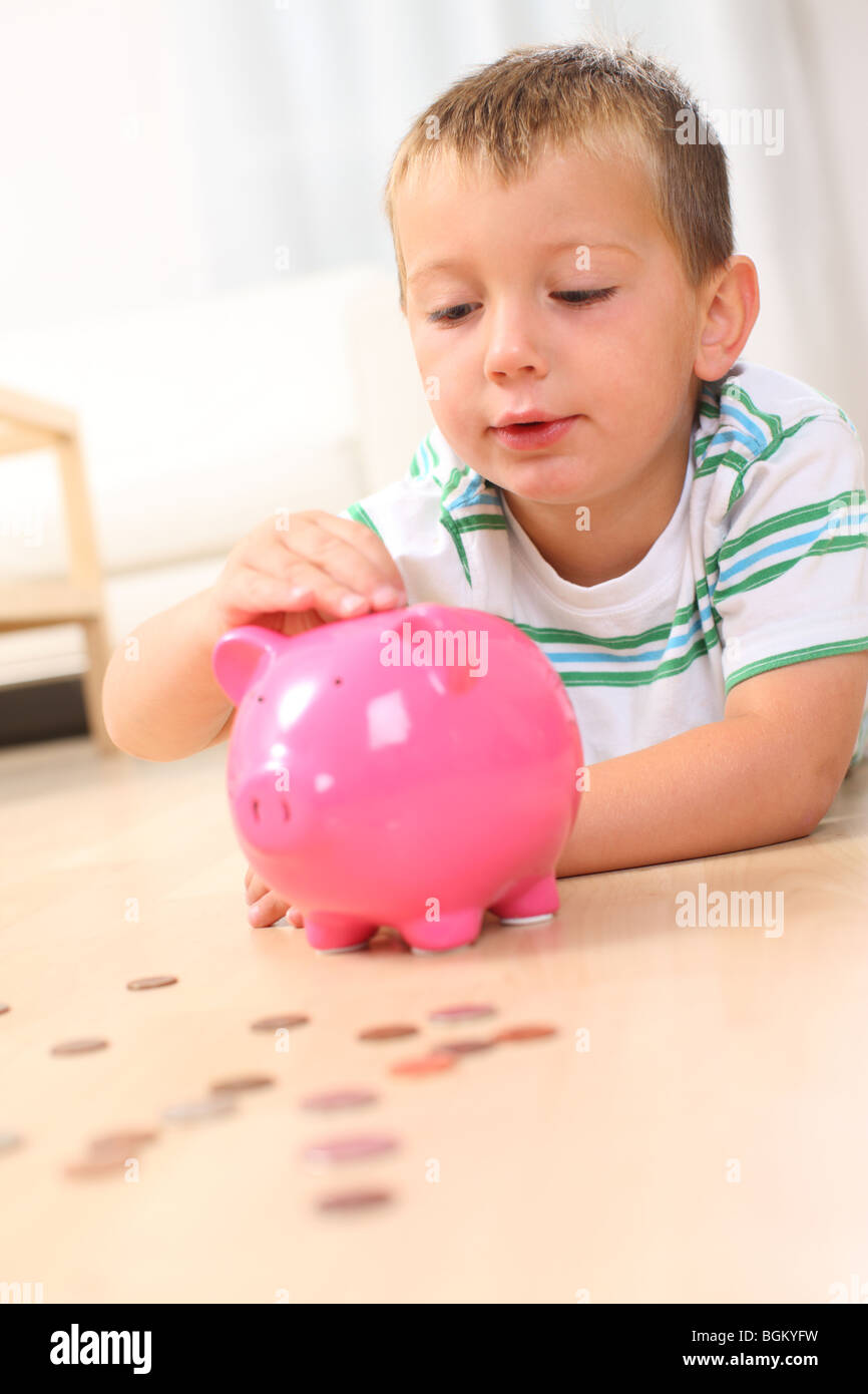 Young boy putting coins in piggy bank Stock Photo