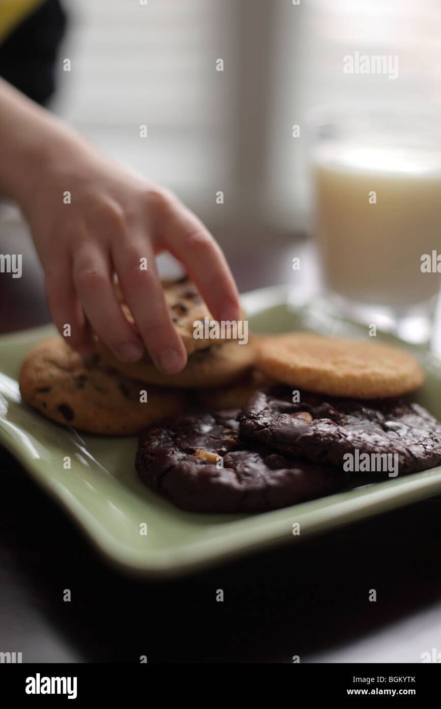 Hand grabbing cookie off plate Stock Photo