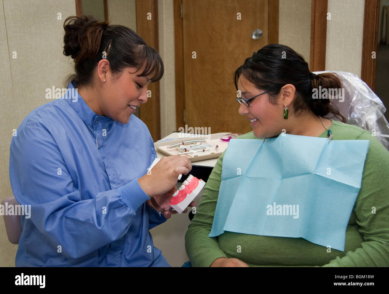 Native American dental hygenist demonstrates proper teeth brushing and health to a tribal member patient at a clinic in Montana Stock Photo