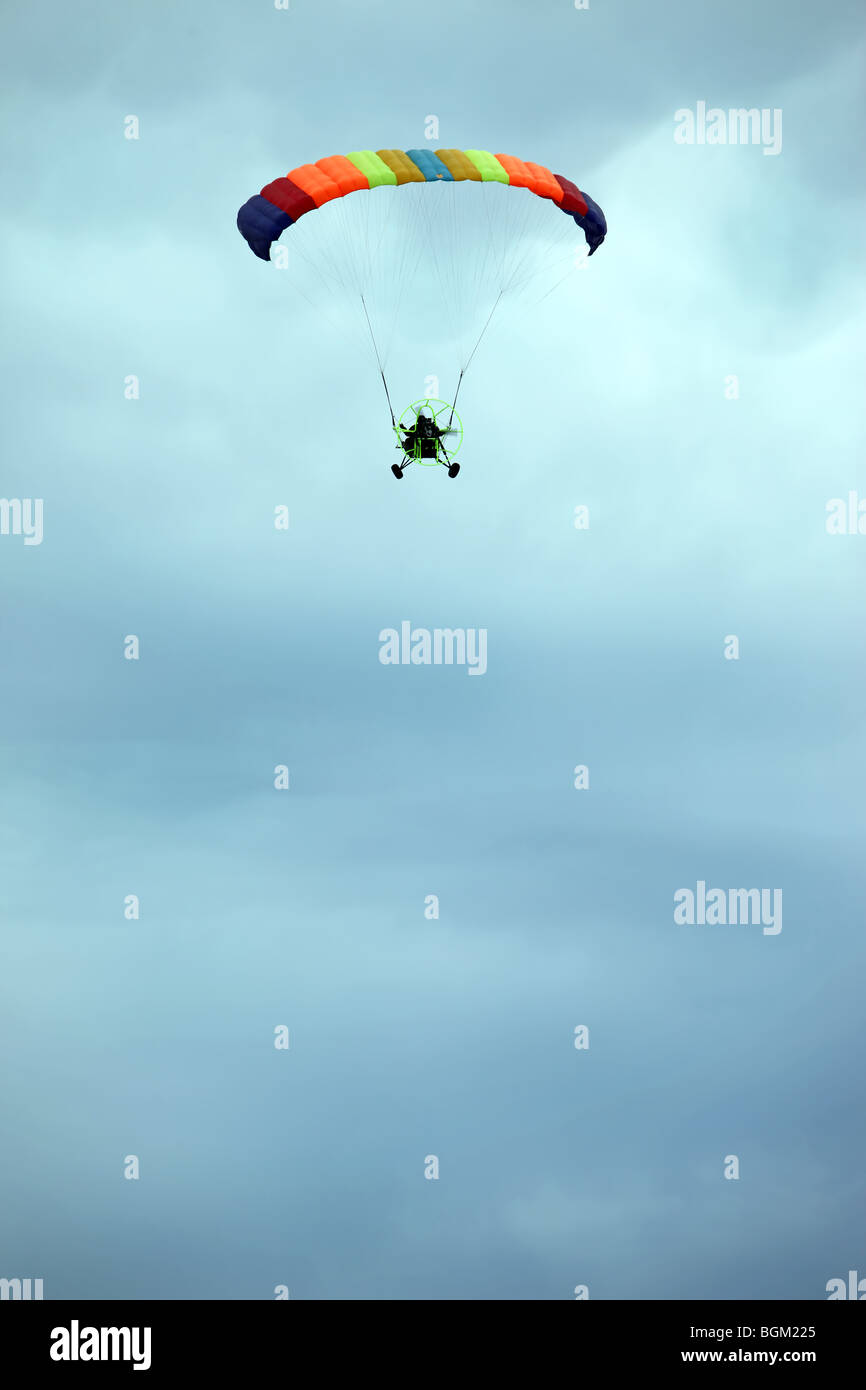 Powered Parachute flying high in a cloudy sky. Vertical format