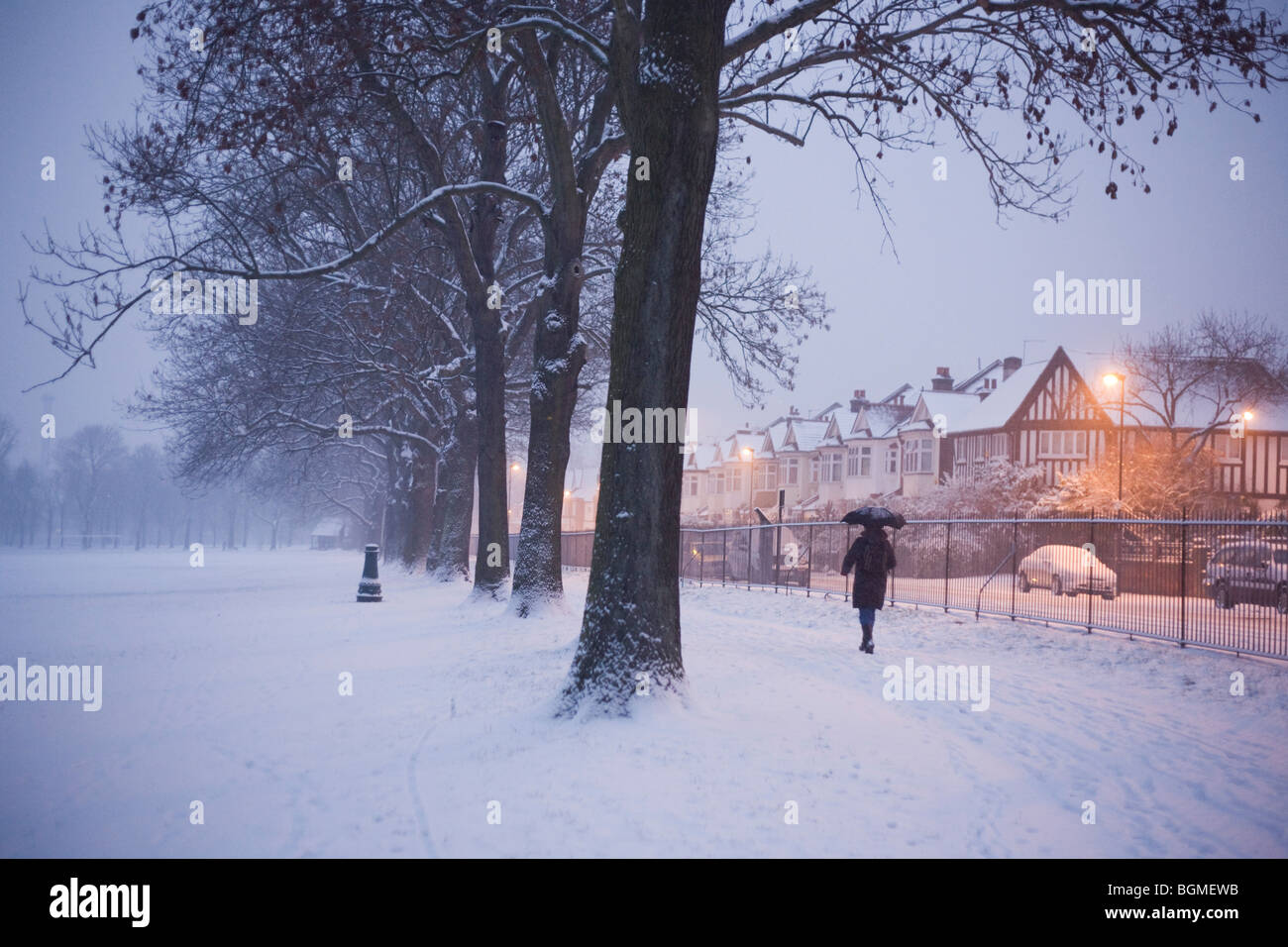 A pedestrian walks through a frozen landscape in Ruskin Park, one early morning during UK snowfalls. Stock Photo