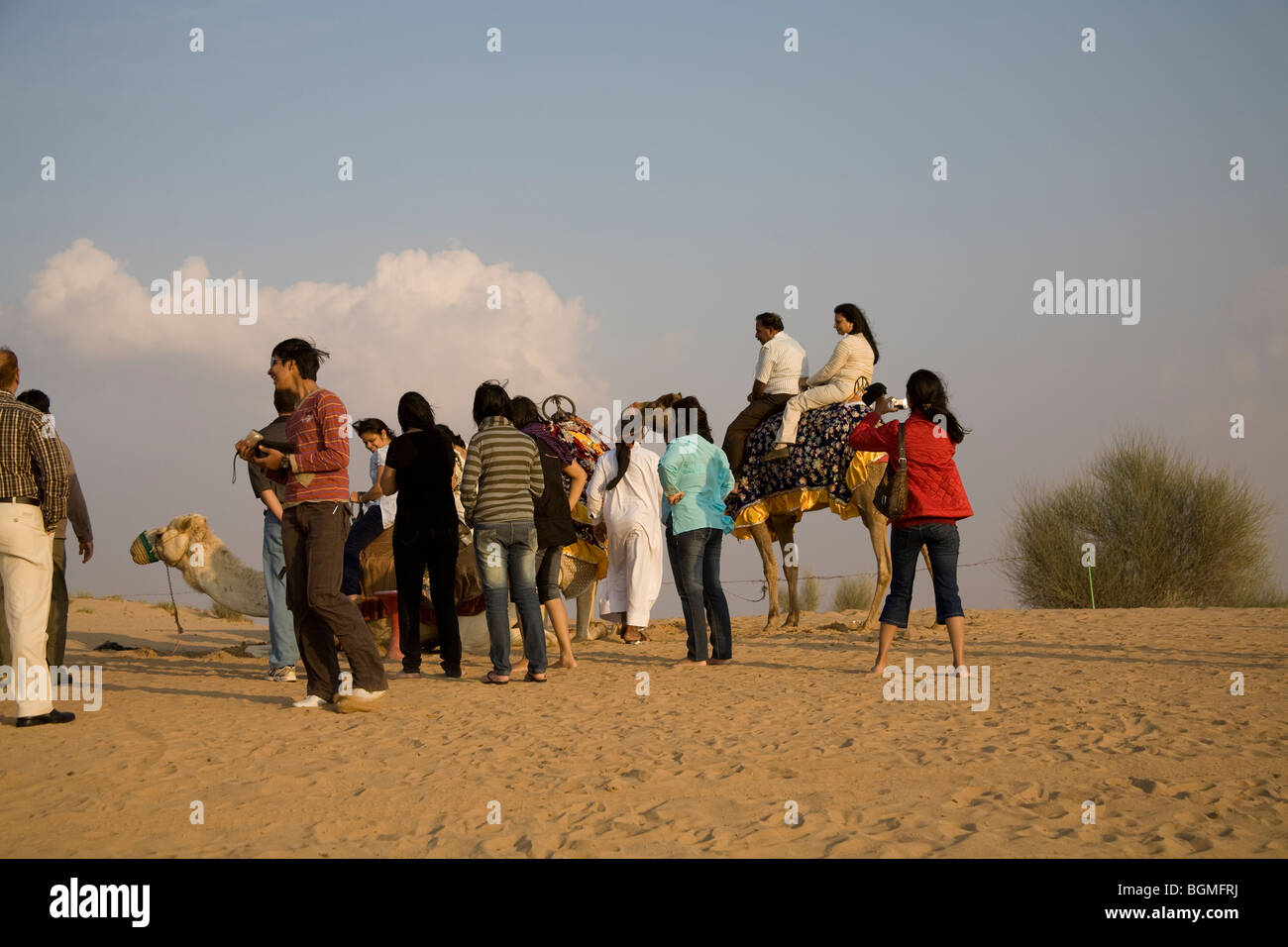 Dubai United Arab Emirates Tourists queuing for camel rides in the desert Stock Photo
