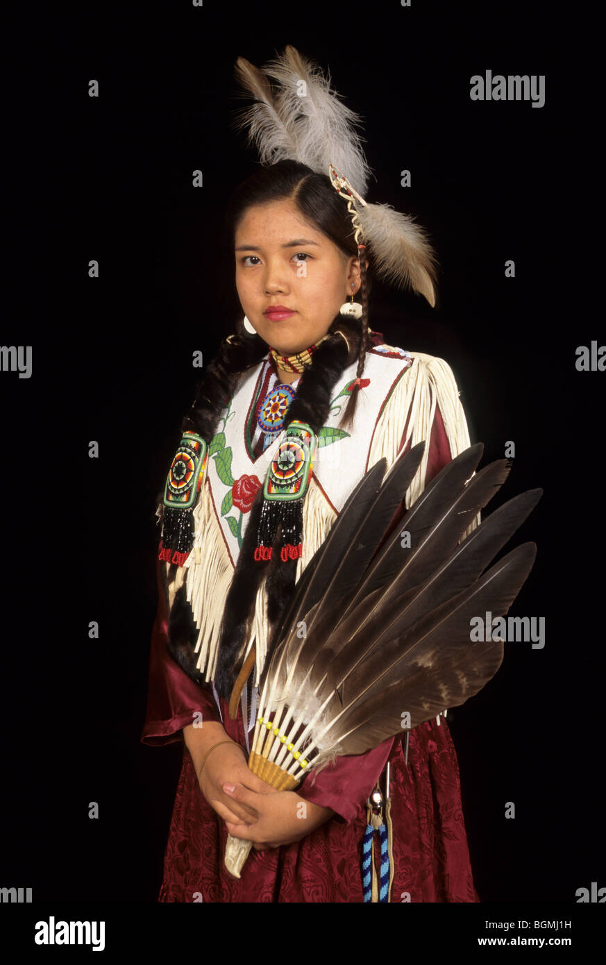 Teenage girl dressed in brain tanned hide dress decorated with beadwork with Native American wooden flute Stock Photo