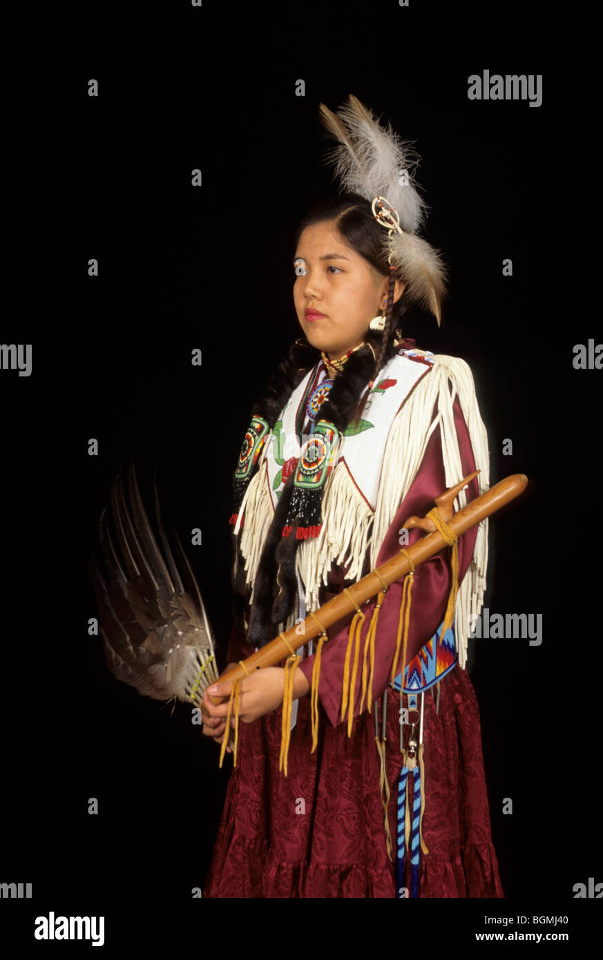 Teenage girl dressed in brain tanned hide dress decorated with beadwork with Native American wooden flute Stock Photo