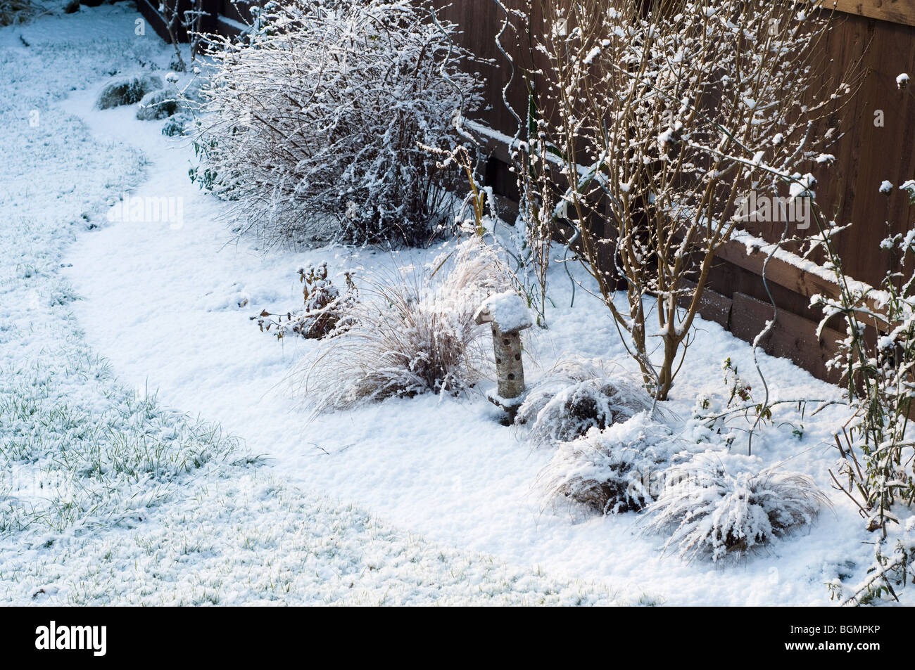 Snowy garden border with ladybird house, Gloucestershire, England Stock Photo