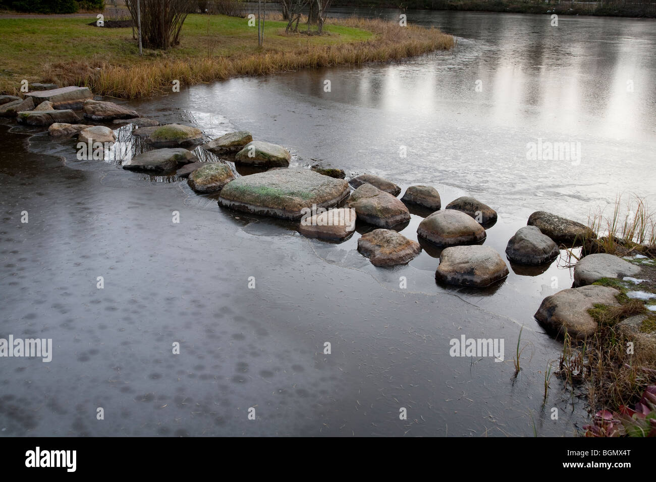 Stepping stones over a frozen garden pond ice skim layer , Finland ...