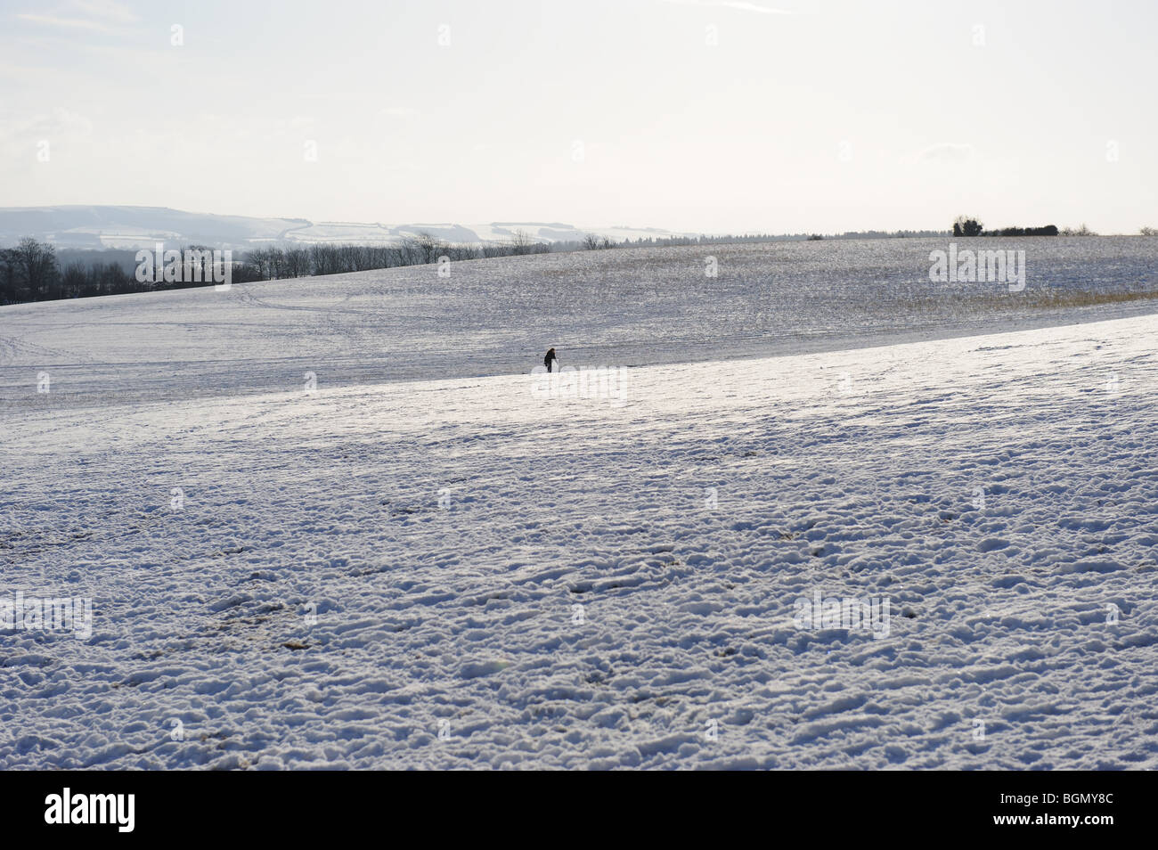 Snow landscape scenic field winter Christmas British England Britain countryside scene solitary walk walking girl sledge Stock Photo