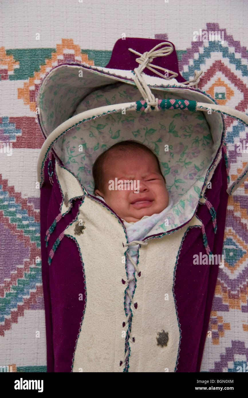 Crying newborn infant bundled and wrapped inside of a traditional cradleboard Stock Photo