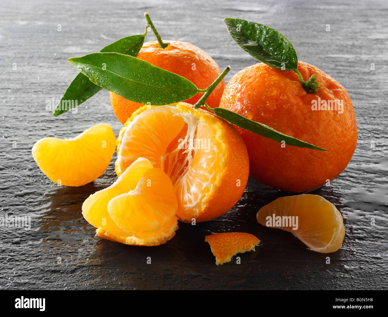 Fresh whole and cut mandarins against a black background Stock Photo