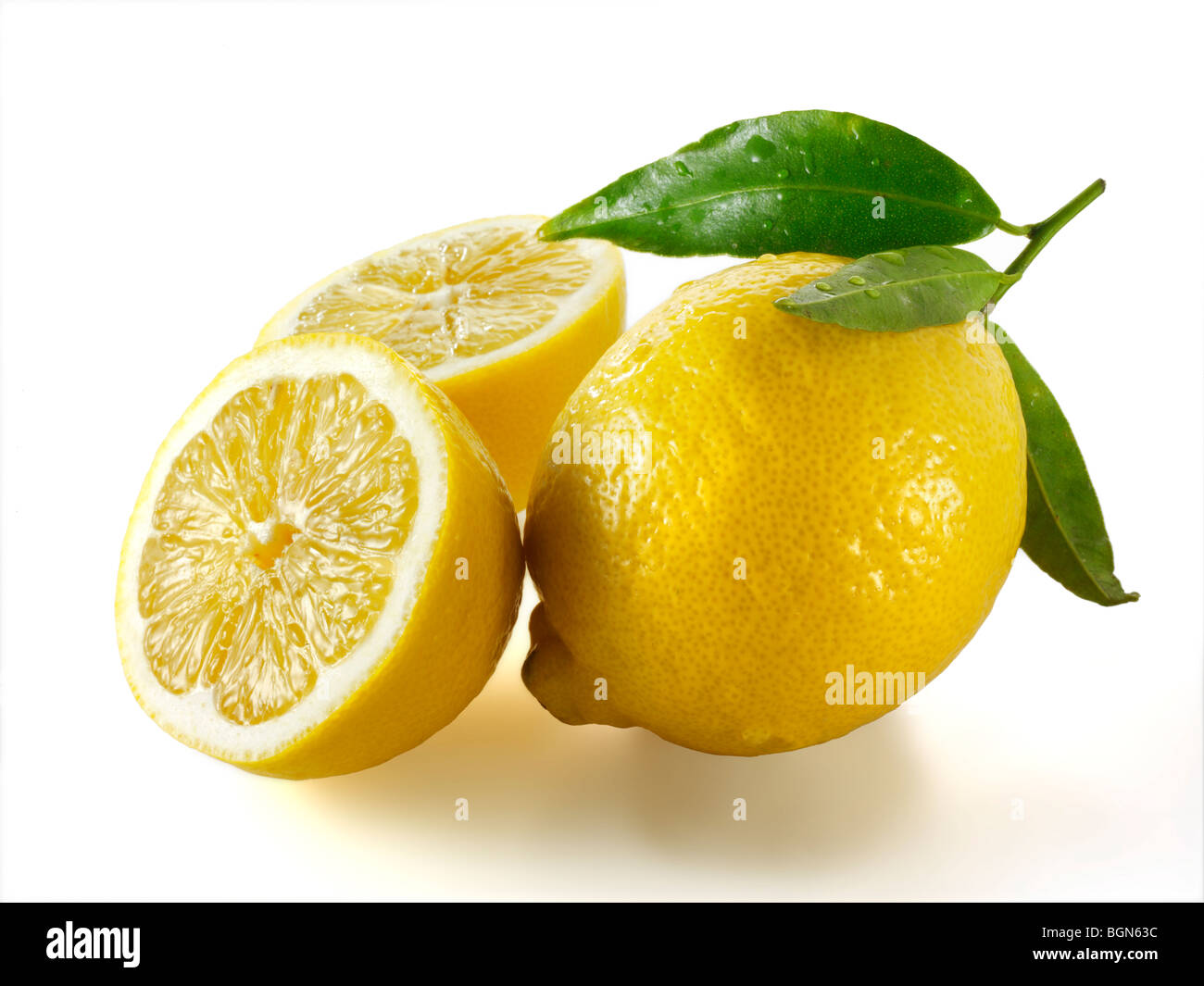 Fresh whole and cut lemons with leaves against white Stock Photo