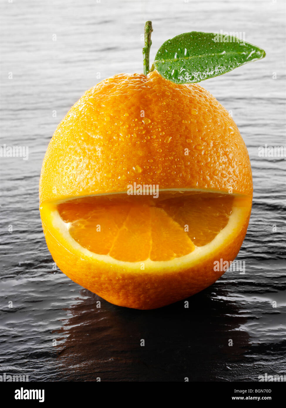 Wole oranges with a smiley face on a black background Stock Photo