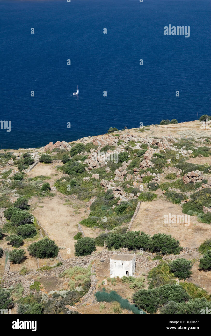 An old whitewashed building looks over the Aegean Sea off Milos Island, Greece Stock Photo