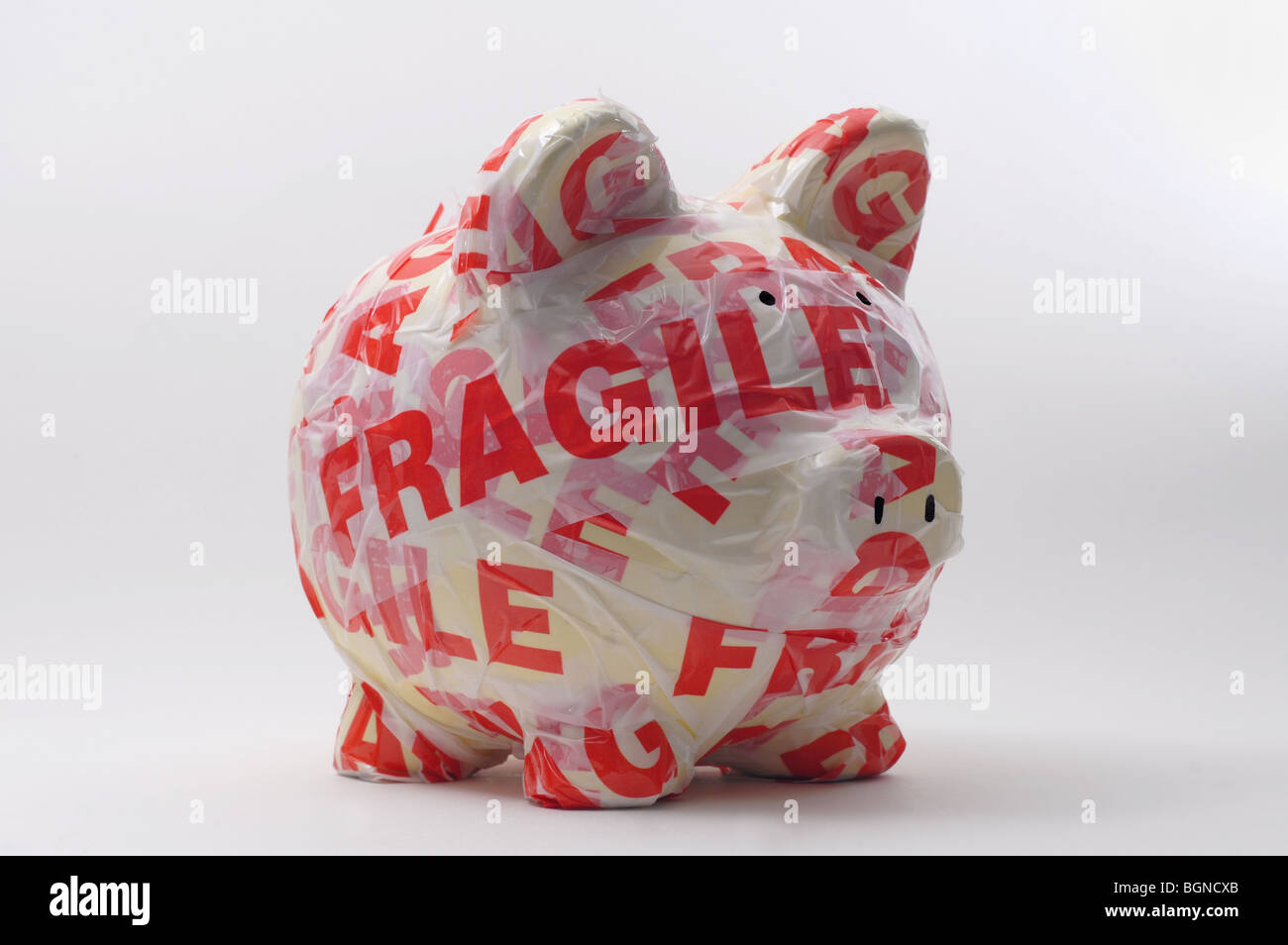 PIGGY BANK WRAPPED IN FRAGILE WARNING TAPE RE SAVINGS/INVESTMENTS/MONEY/CASH THE ECONOMY CASH MONEY HOUSEHOLD BUDGETS UK Stock Photo