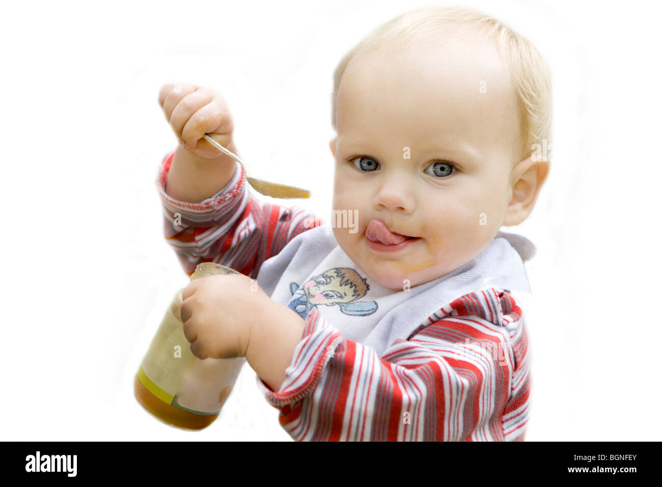Beautiful blue eyed blond baby eating apple sauce with a spoon isolated