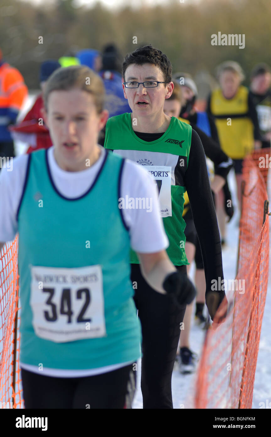 Women runners in finishing funnel at end of cross-country race in snow Stock Photo