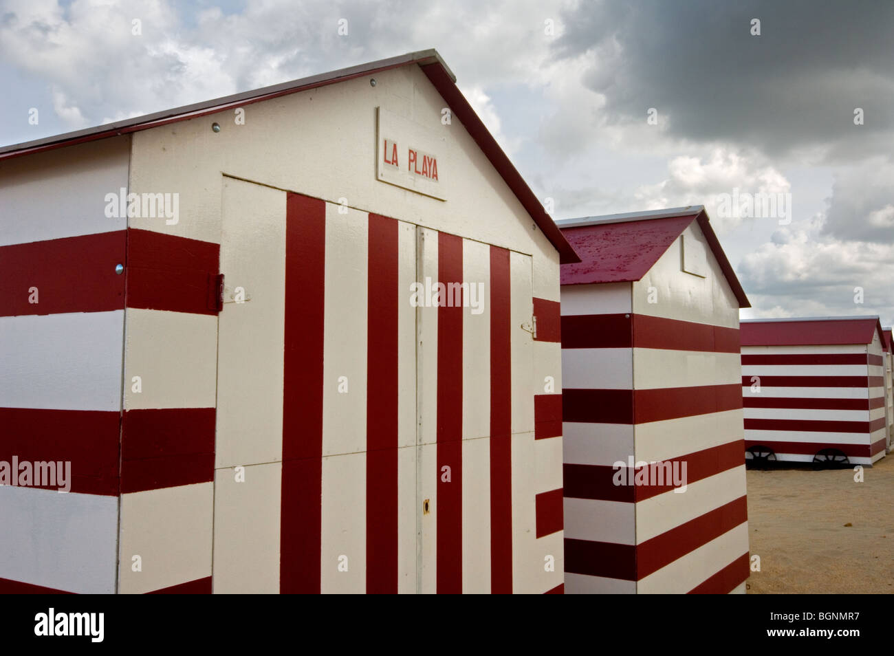 Row Of Colourful Red White Striped Beach Cabins On Wheels Along