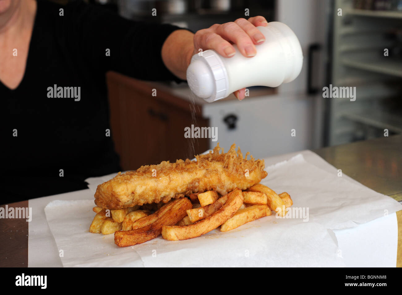Putting salt on fish and chips Stock Photo