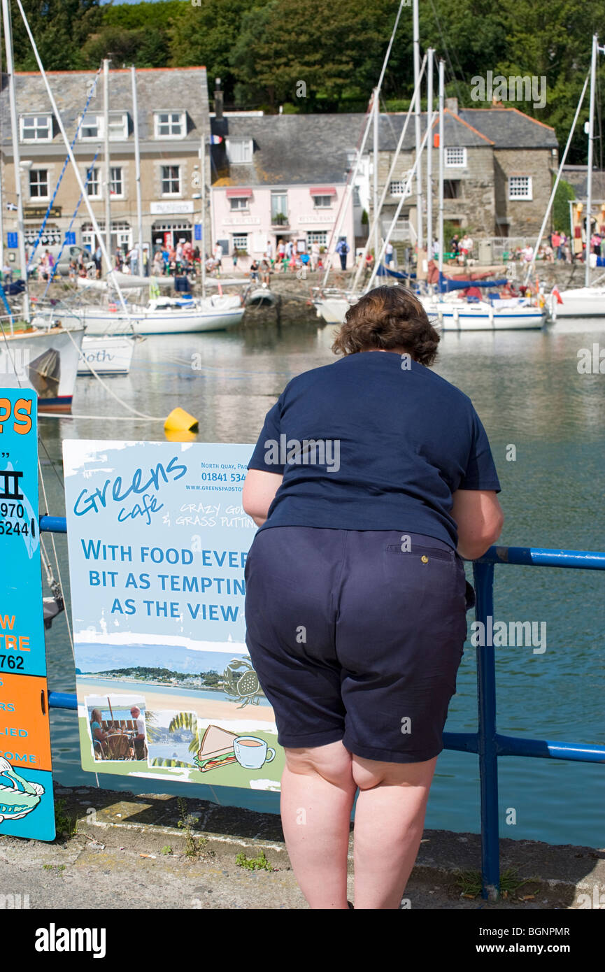 A generously sized woman inadvertently standing next to a sign referring to the view which happens to be of the womans rear. Stock Photo