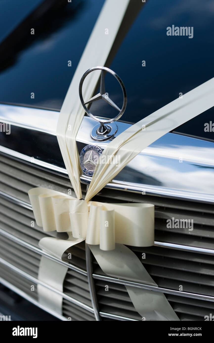 Old, new, hired and blue - a well used Mercedes wedding car decked out with a ribbon for wedding-day hire Stock Photo