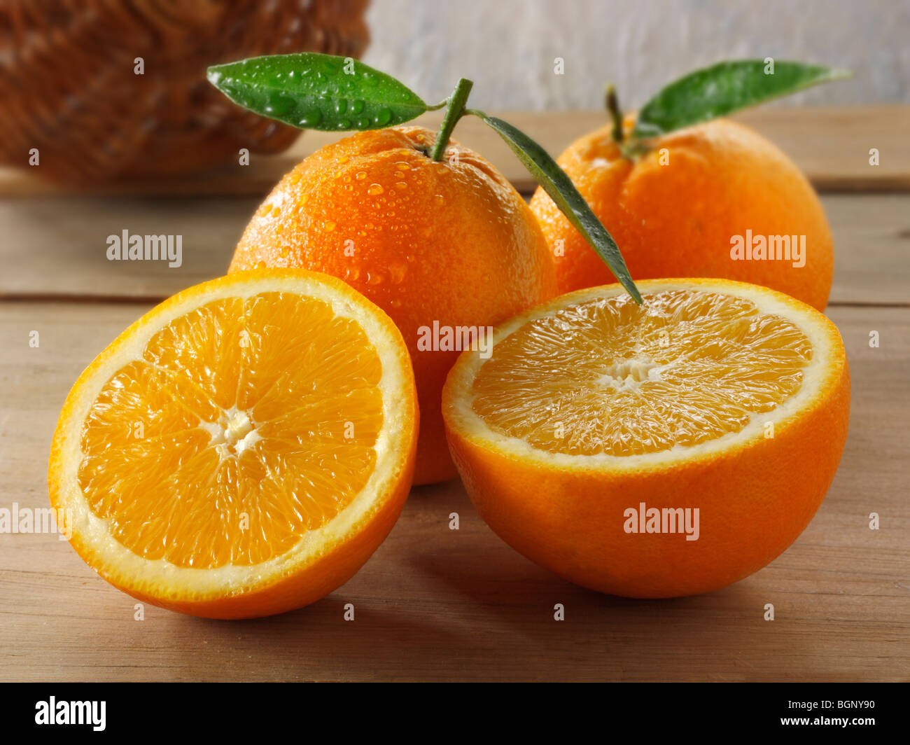 Whole and cut fresh oranges  with leaves  in a kitchen setting Stock Photo