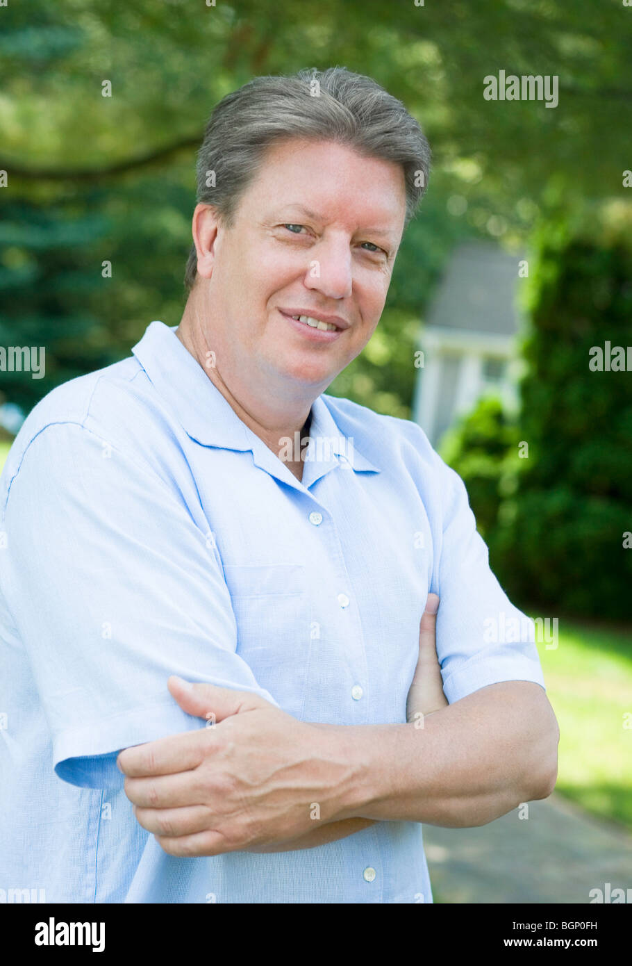 Portrait of a mature man standing with his arms crossed and smiling ...