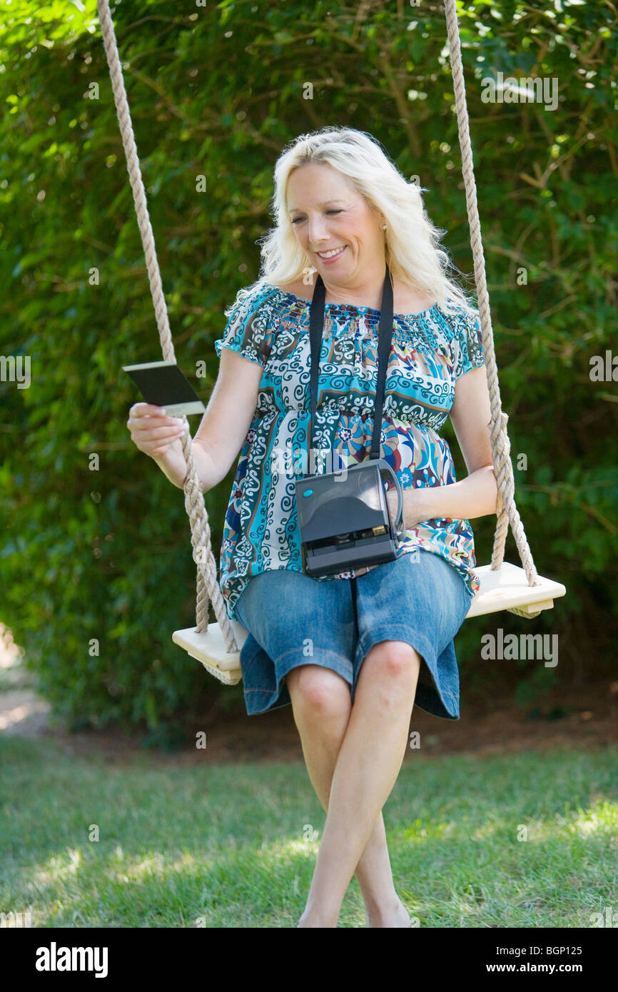 Mature woman sitting on a swing and looking at a photograph Stock Photo ...