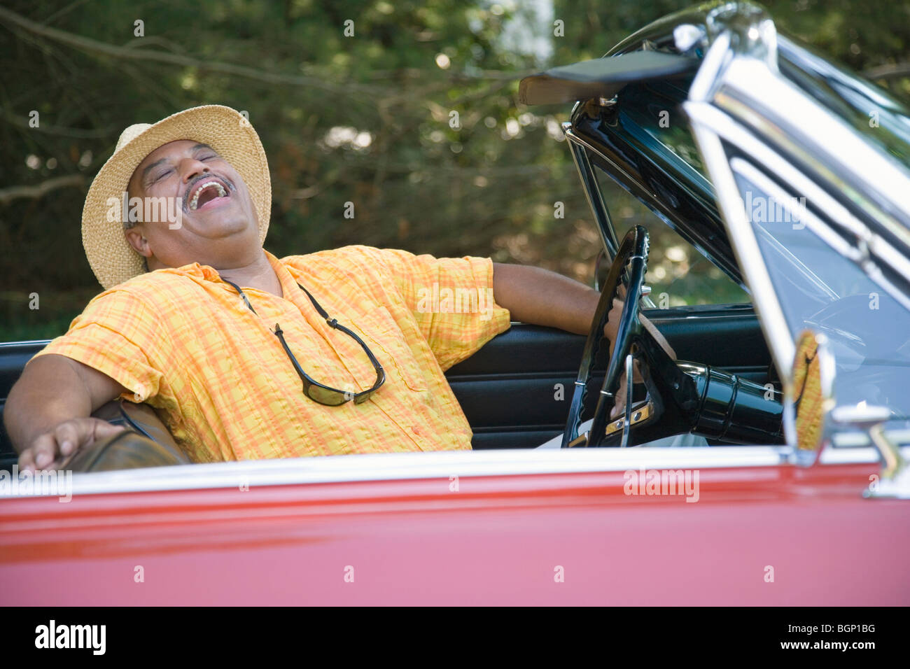 Senior man sitting in a convertible car and laughing Stock Photo