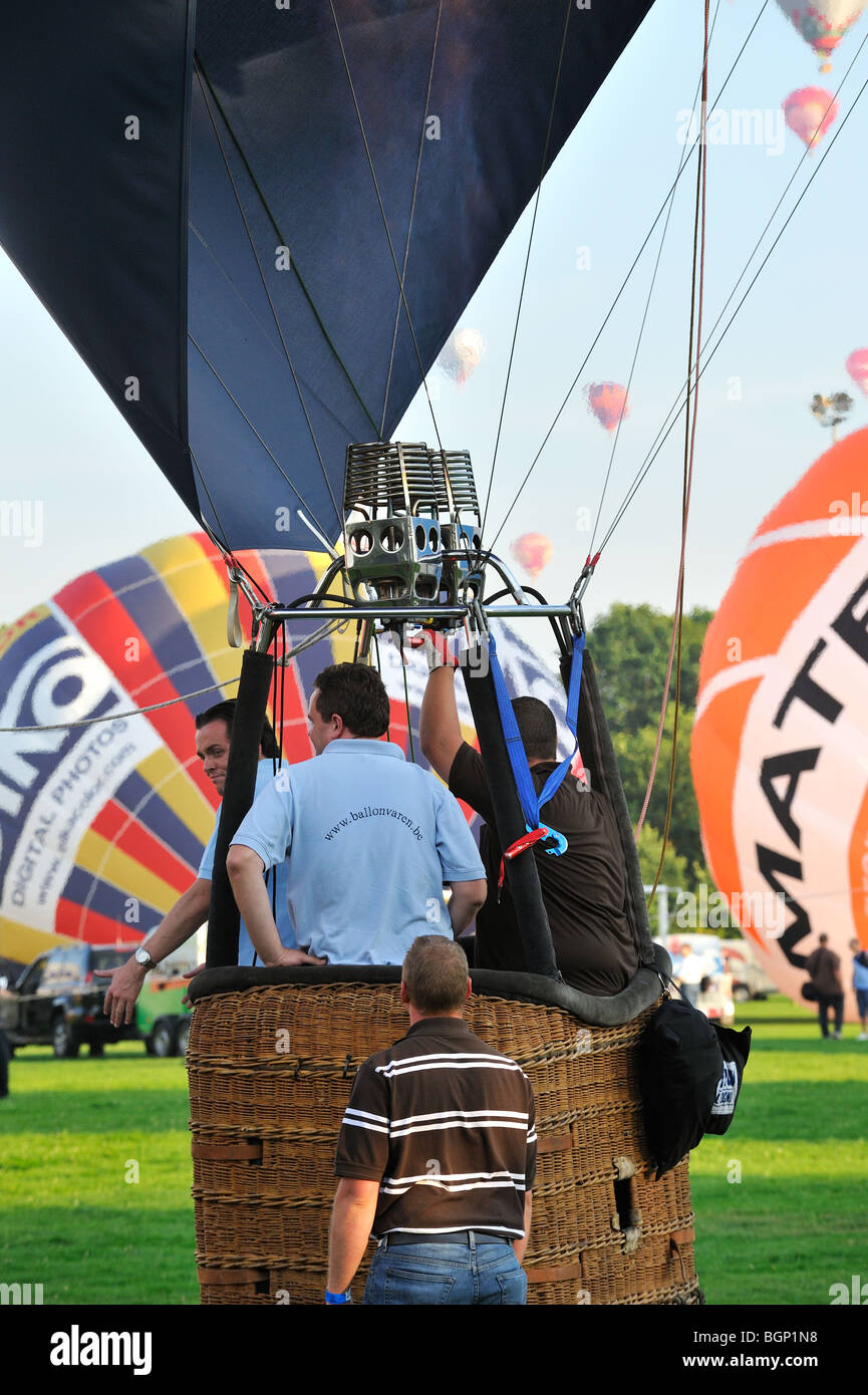 Pilot and passengers in basket of hot-air balloon preparing to take-off during hot air ballooning meeting Stock Photo