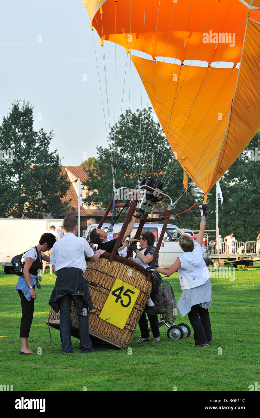 Balloonists / Aeronauts inflating hot-air balloon with propane burner during hot air ballooning meeting Stock Photo