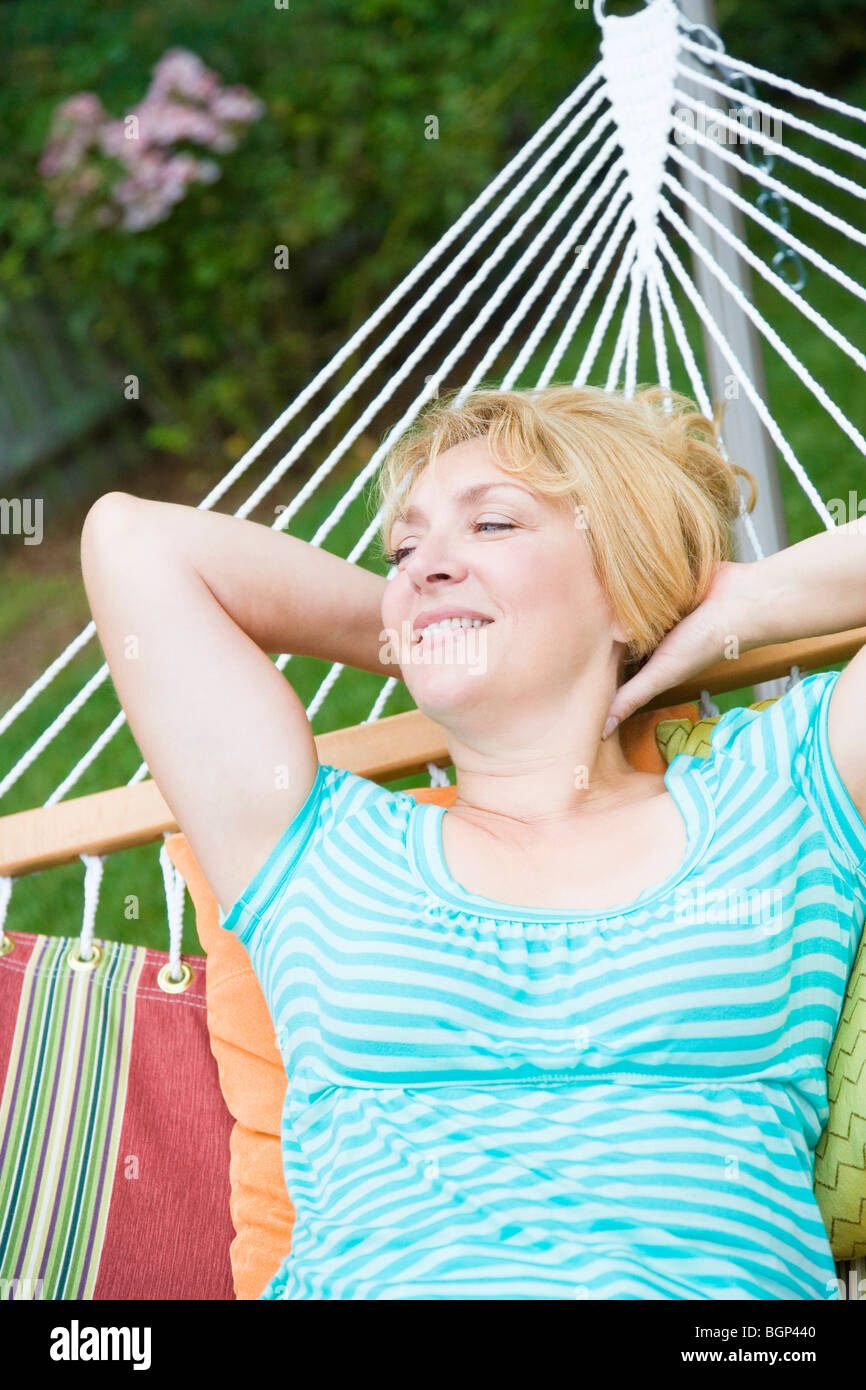 Mature woman lying in a hammock and smiling Stock Photo - Alamy