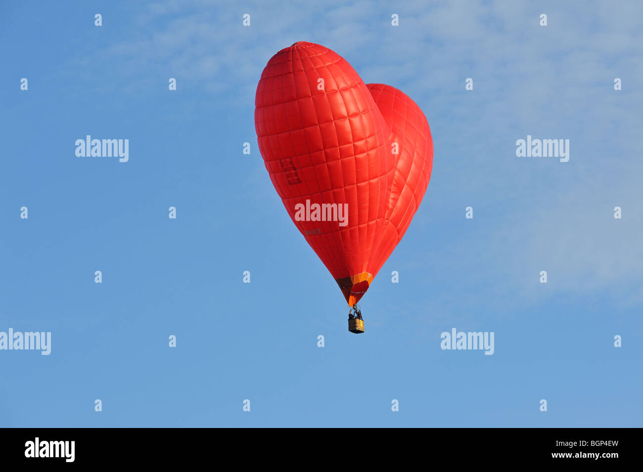 Balloonists / Aeronauts flying in red heart shaped hot-air balloon during ballooning meeting Stock Photo