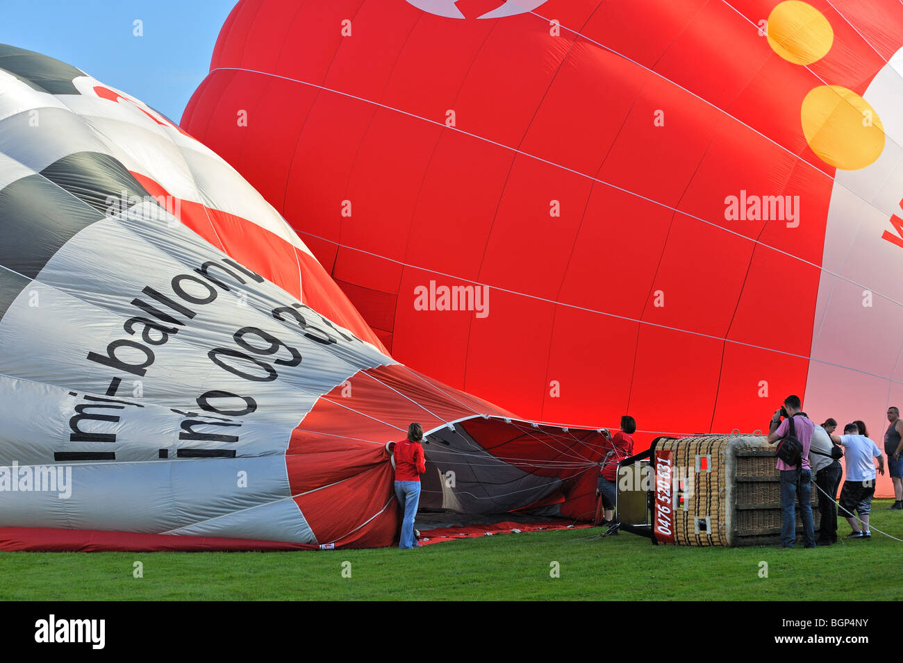 Hot air balloonists / Aeronauts preparing and inflating hot-air balloon with propane burners during ballooning meeting, Belgium Stock Photo