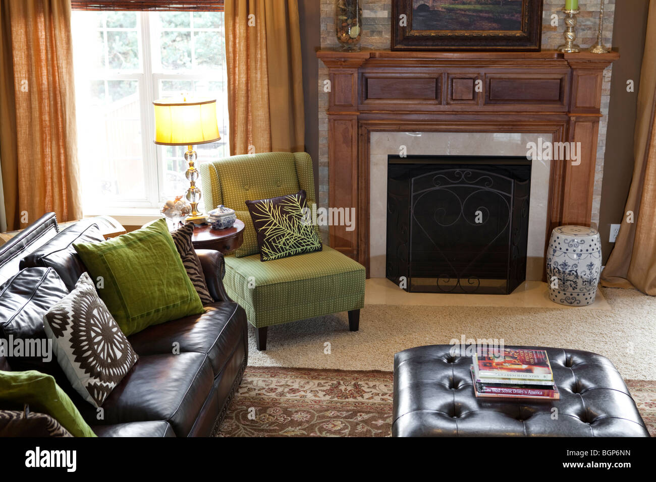 Sitting room with leather sofa and coffee table, upholstered fabric armchair, fireplace and carpeted floor Stock Photo