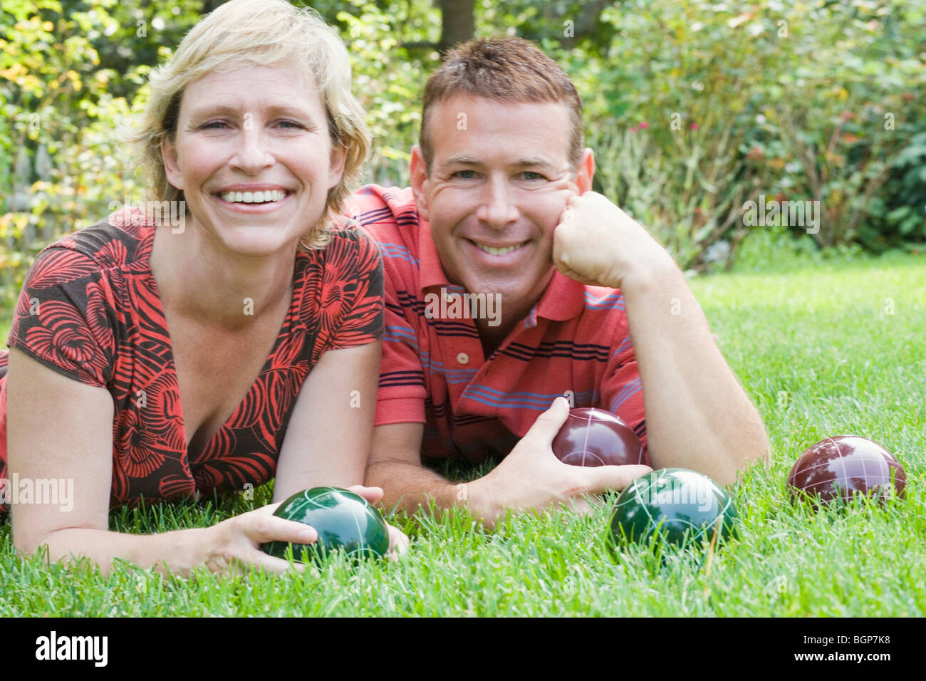 Portrait of a mature couple lying on grass and holding balls Stock ...