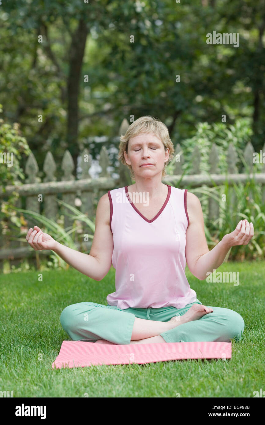 Mature woman doing yoga in a lawn Stock Photo