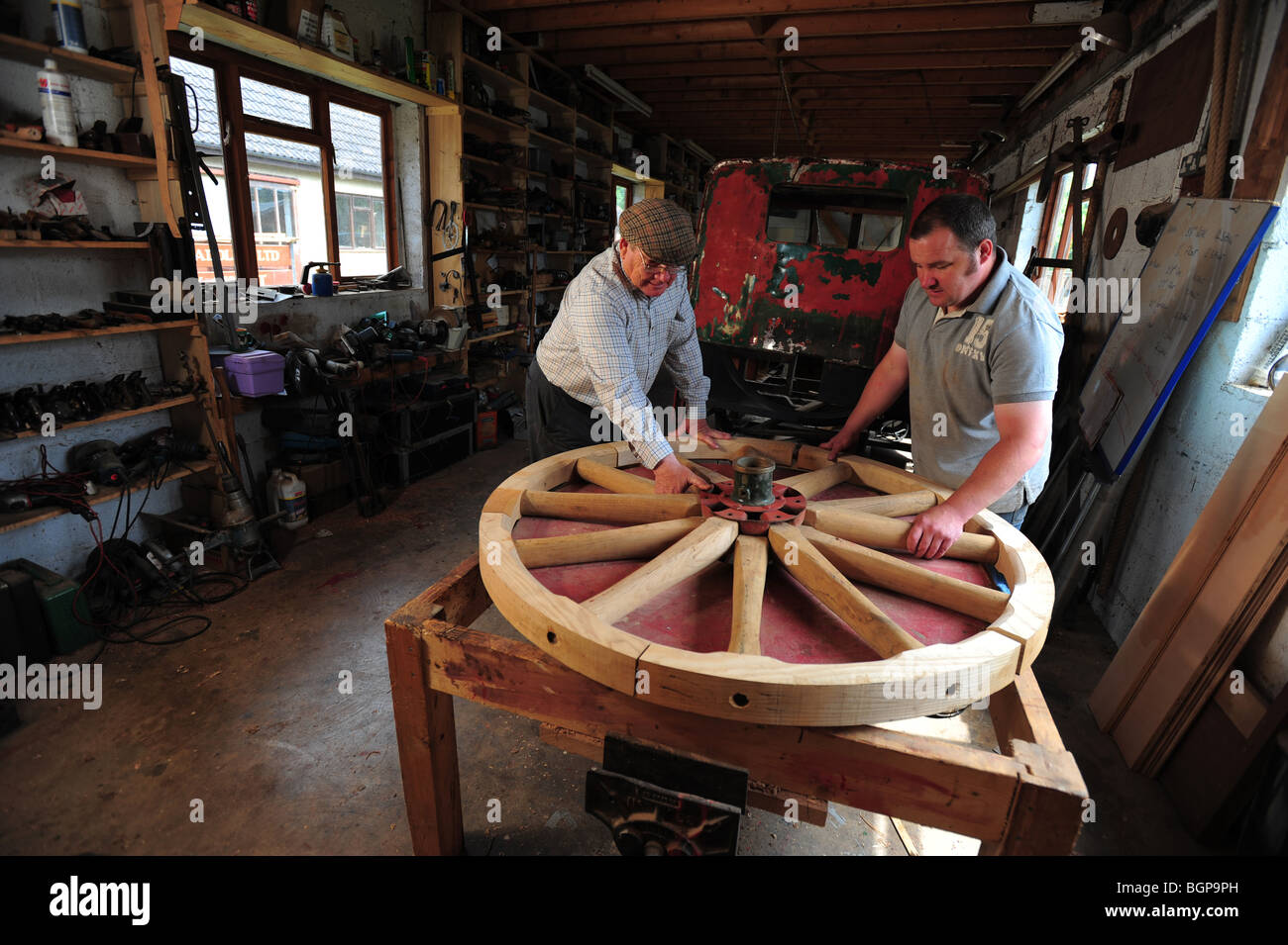 two wheelwrights with a finished carriage wheel in a workshop at at Mike Rowland Wheelwright and coachbuilders, in Colyton. Stock Photo