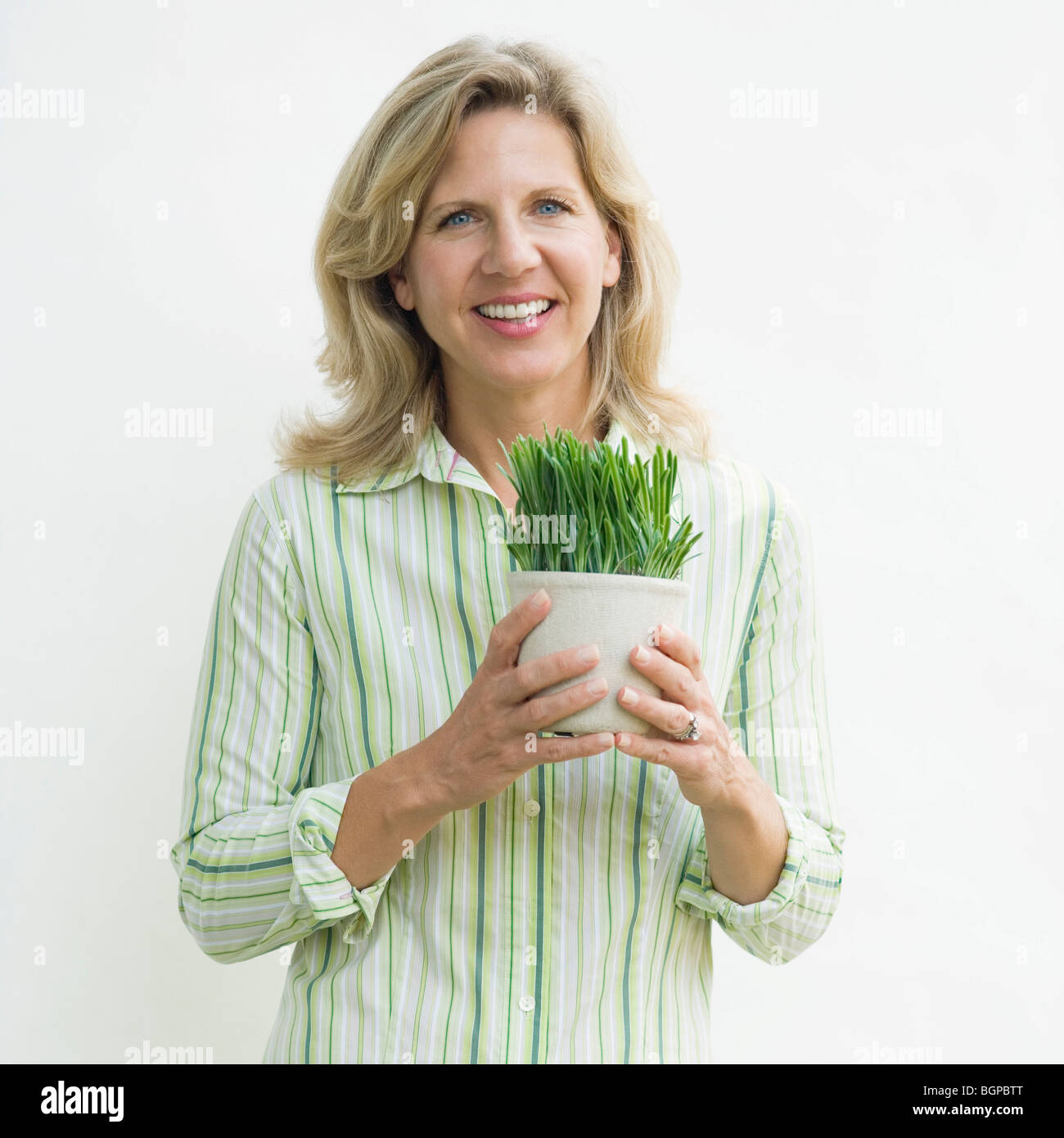 Portrait of a mature woman holding a potted plant and smiling Stock ...