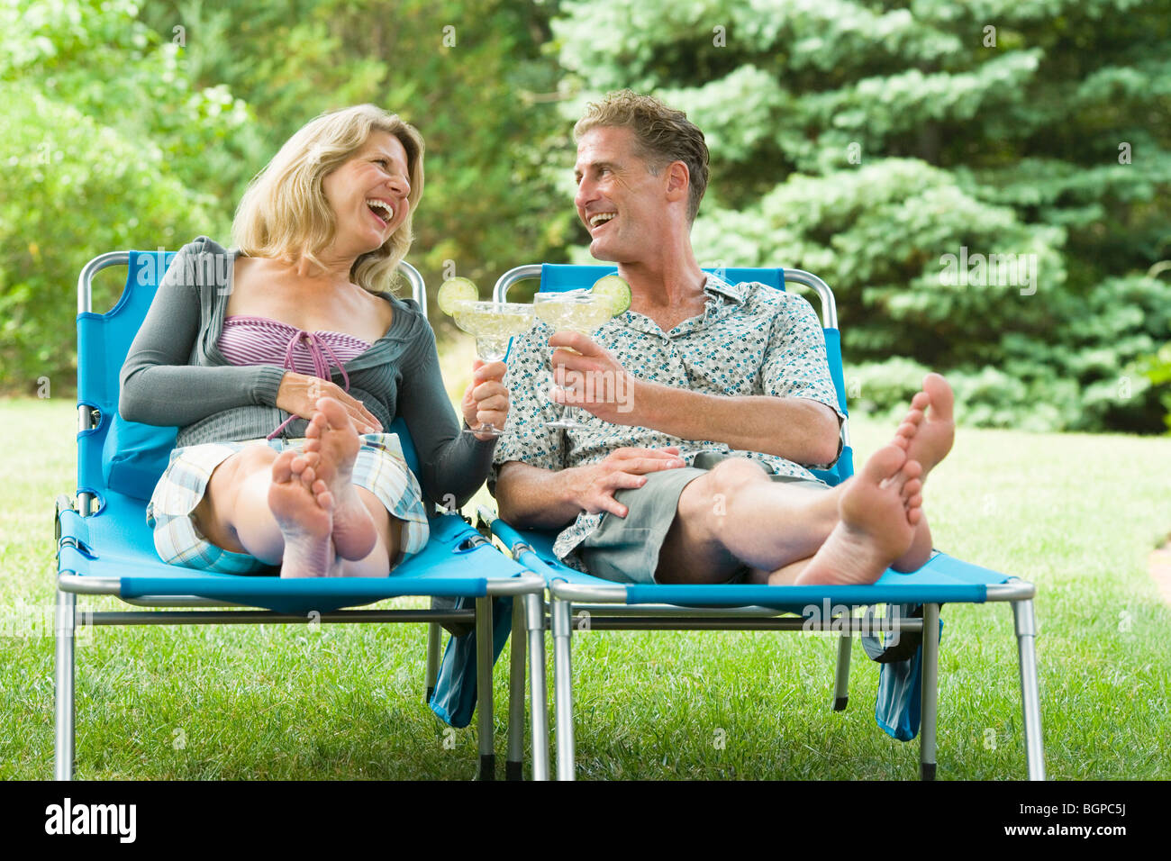 Mature couple reclining on lounge chairs and toasting with glasses of