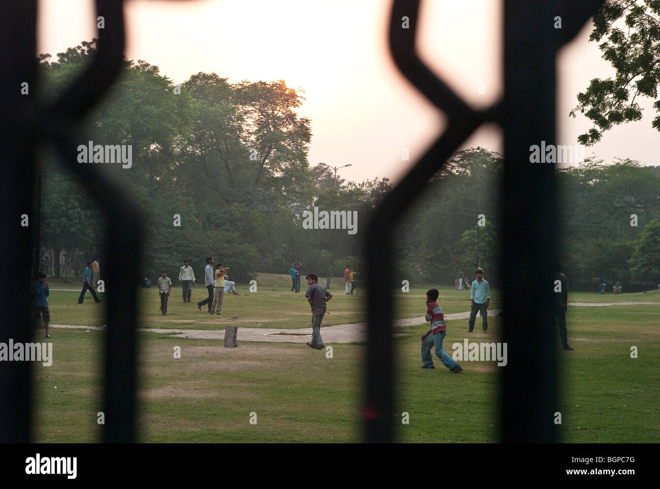 Children playing cricket in a park at dusk, Delhi, India Stock Photo
