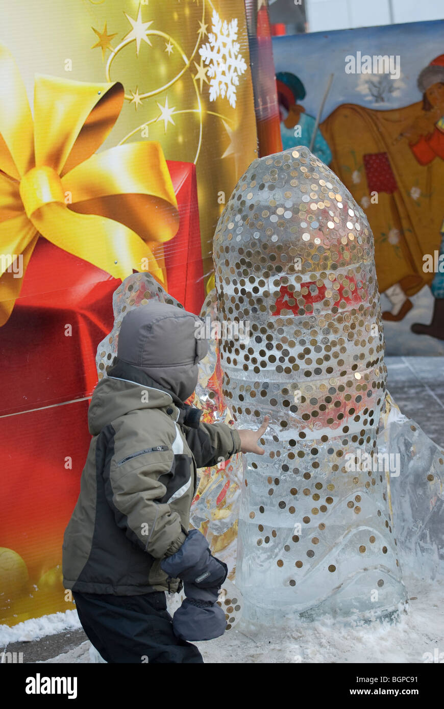 A little boy paste coins to an ice sculpture Stock Photo