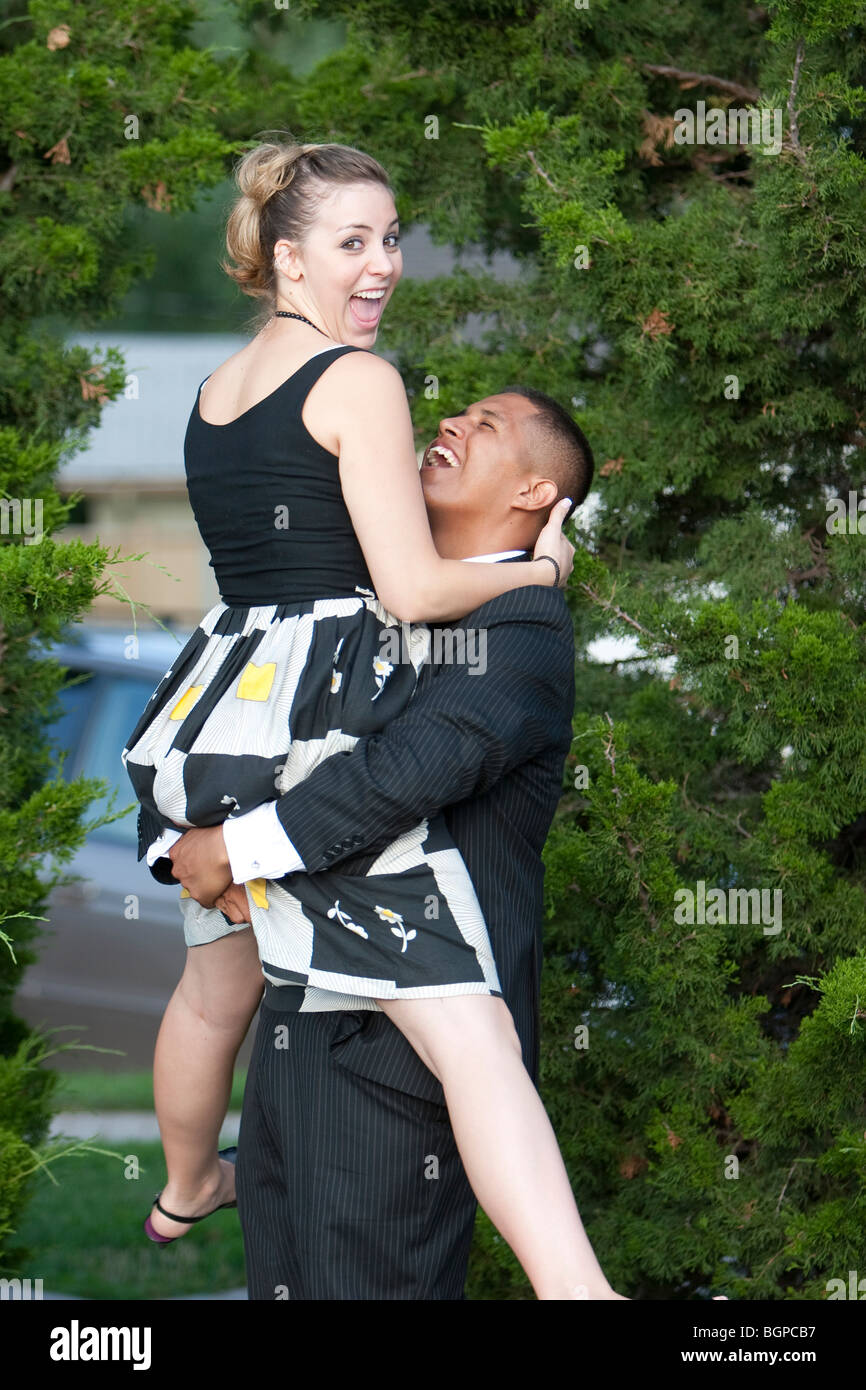 A man in a suit lifts his wife into the air. Stock Photo