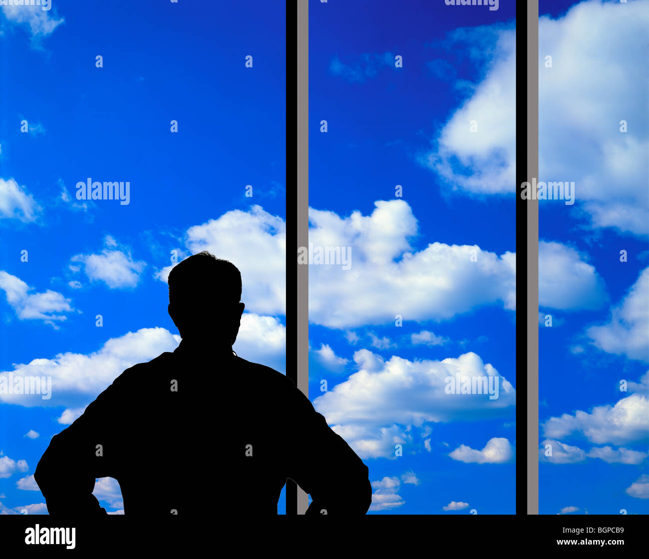 man looking at clouds through large glass window Stock Photo