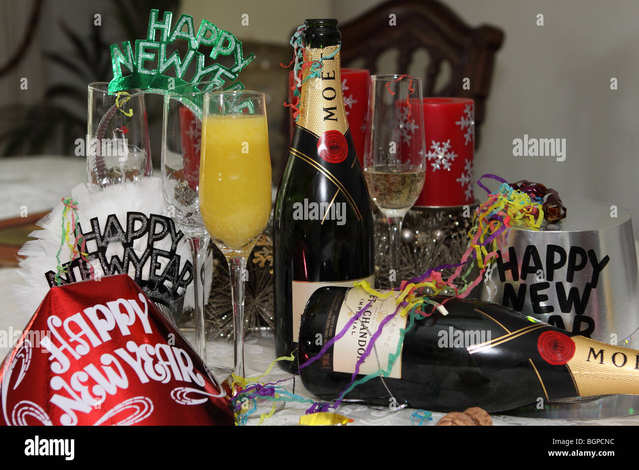 Champagne bottles and New Years eve hats and glasses with bucks fizz or mimosa Stock Photo
