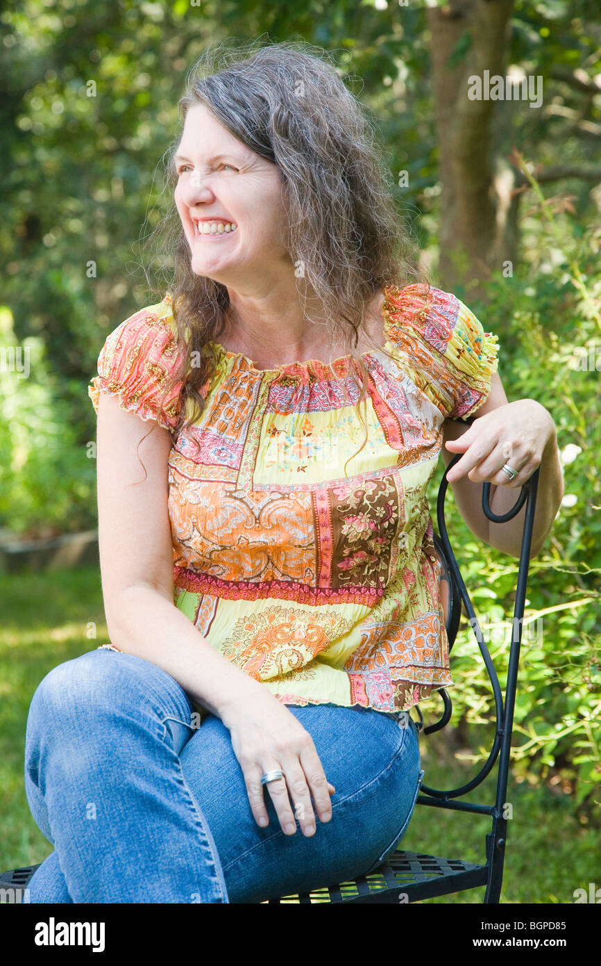 Mature woman sitting on a chair and smiling Stock Photo - Alamy